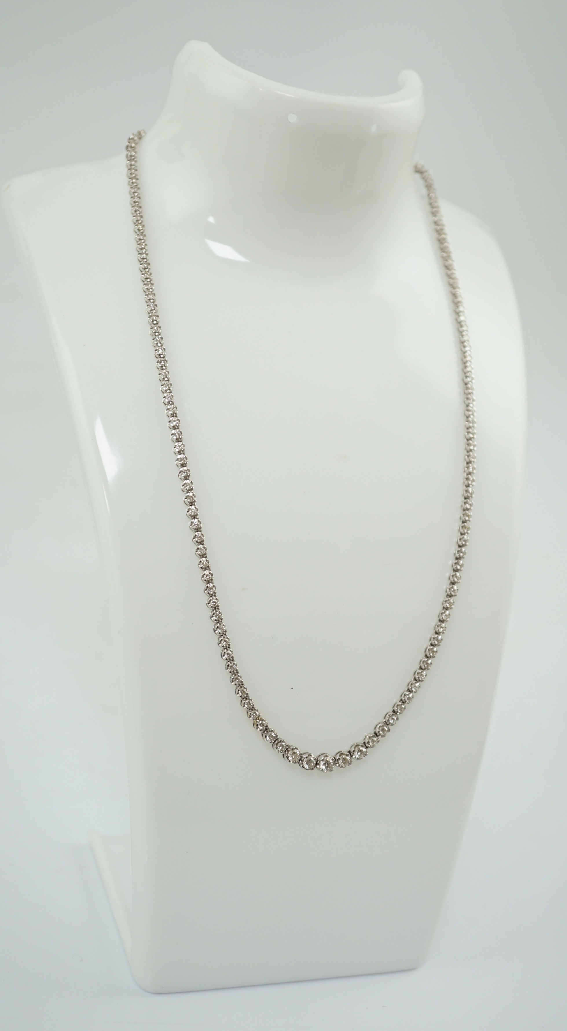 A modern 18k gold and illusion set diamond line necklace, set with diamond chips and five graduated larger stones, 40cm, gross weight 17 grams. Condition - poor to fair (old repair to one link)